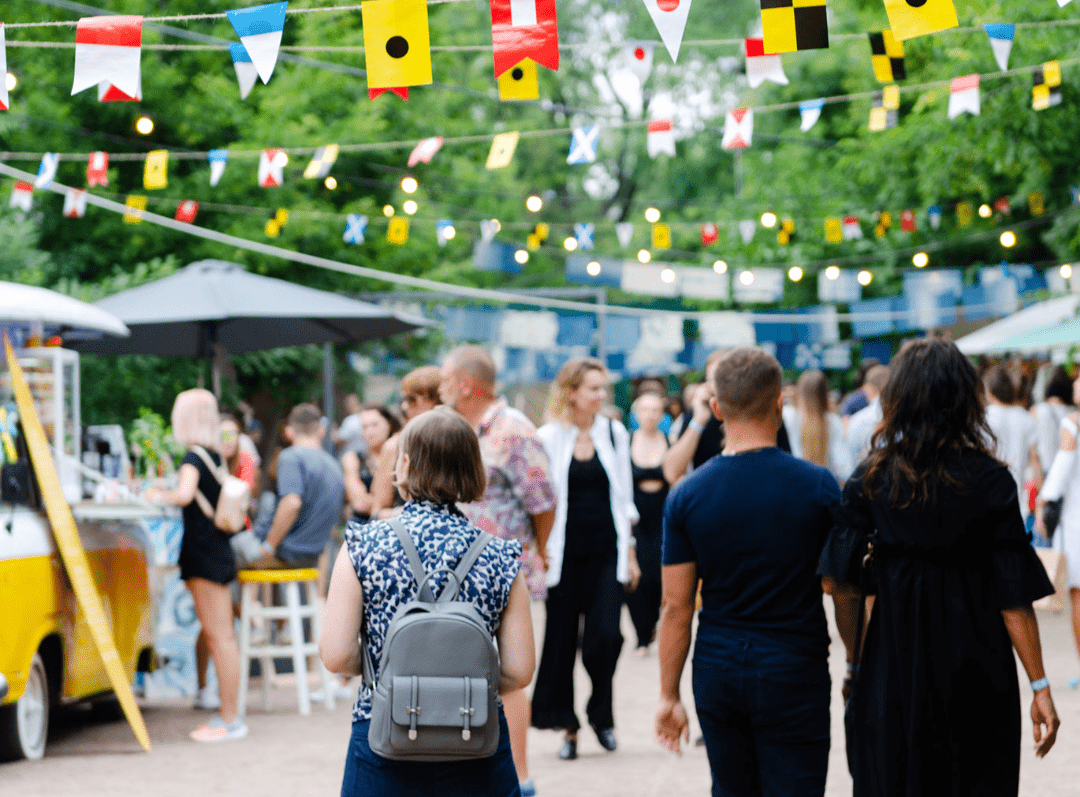 Menschen gehen auf einem Stadtfest spazieren. Im Hintergrund sind Foodtrucks.